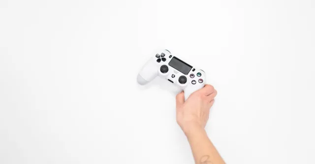 A white gaming controller held by a hand against a minimal white background, perfect for tech and gaming themes.