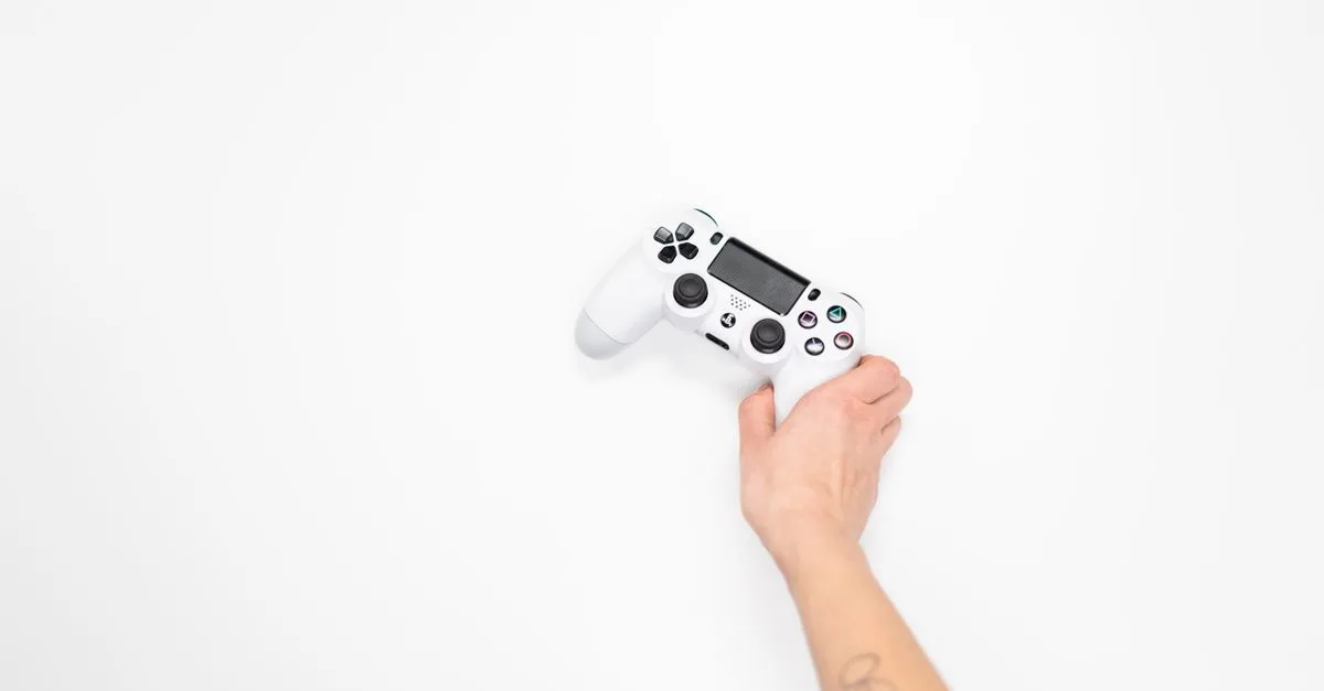 A white gaming controller held by a hand against a minimal white background, perfect for tech and gaming themes.