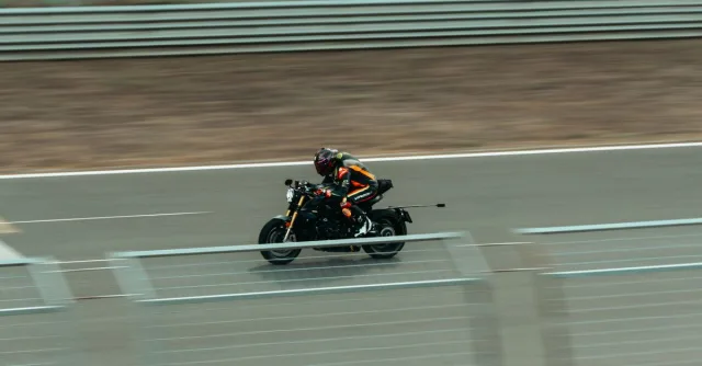 Blurred image of a motorcyclist racing at high speed on an outdoor track.