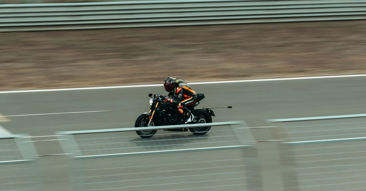 Blurred image of a motorcyclist racing at high speed on an outdoor track.