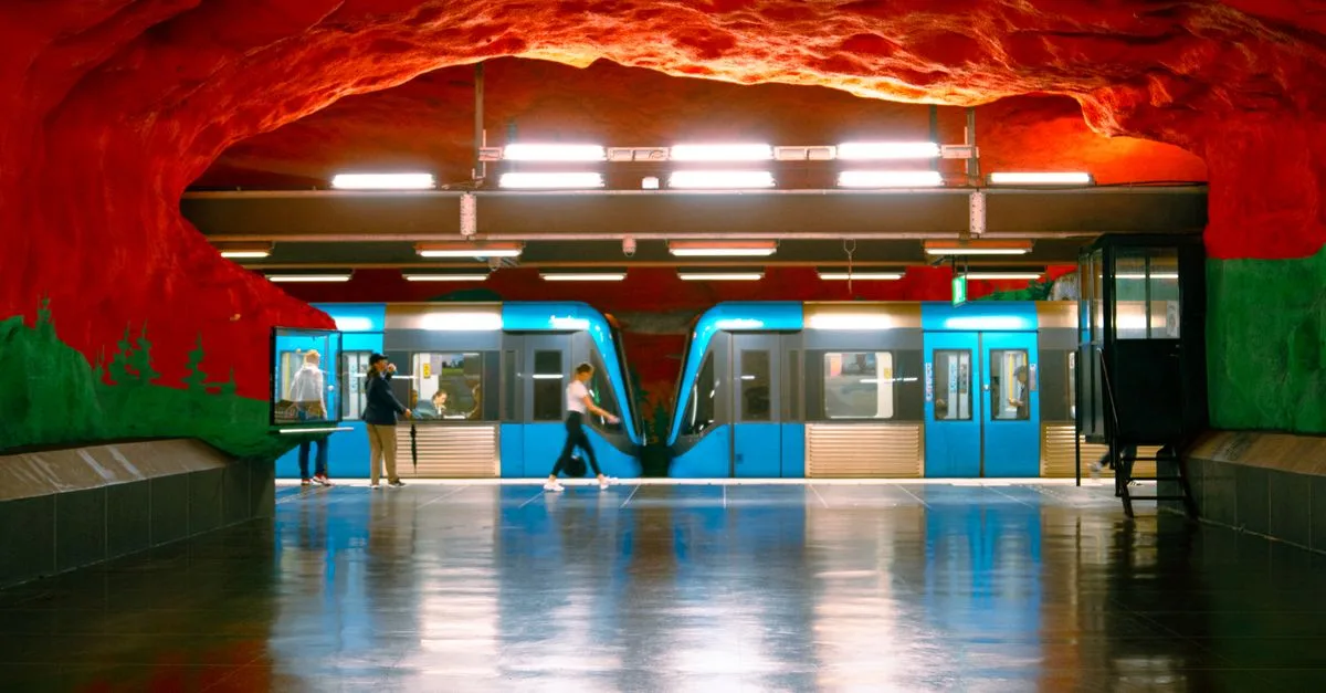Vibrant artwork at a Stockholm metro station with people and a blue train.