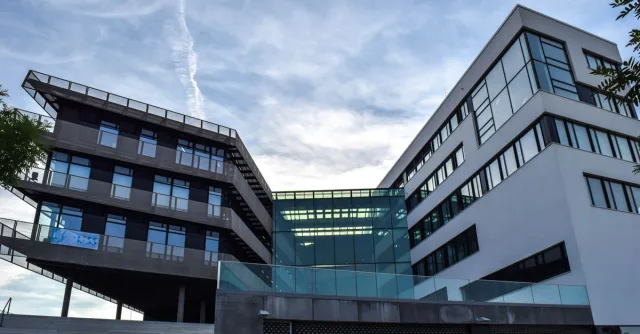 A modern glass-facade building against a blue sky, featuring innovative architecture.