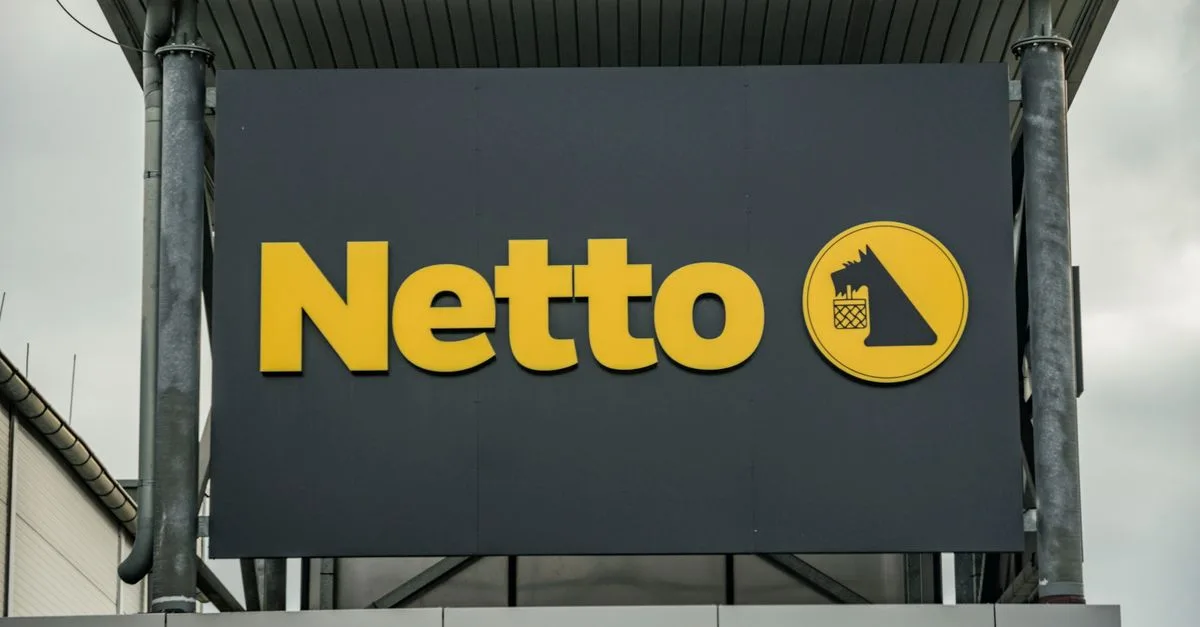 Exterior view of Netto supermarket branding, featuring yellow logo on dark background.