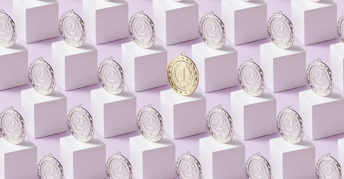 A gold medal stands out among silver medals on white cubes, showcasing uniqueness.