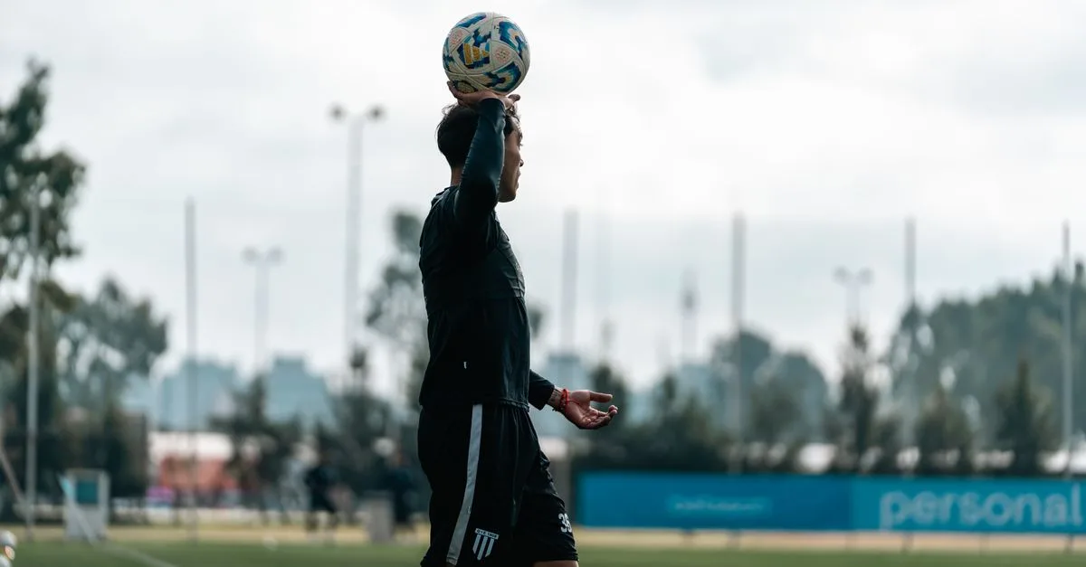 Football player in sports uniform prepares for a throw-in during a practice session outdoors.