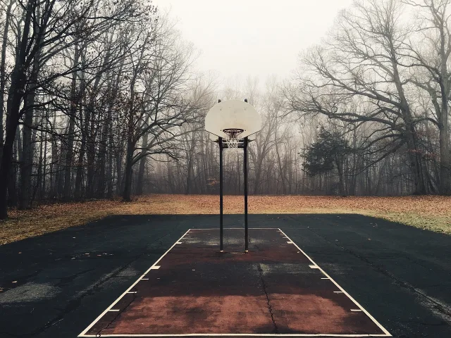 A professional basketball court with polished hardwood floors and stadium lighting.