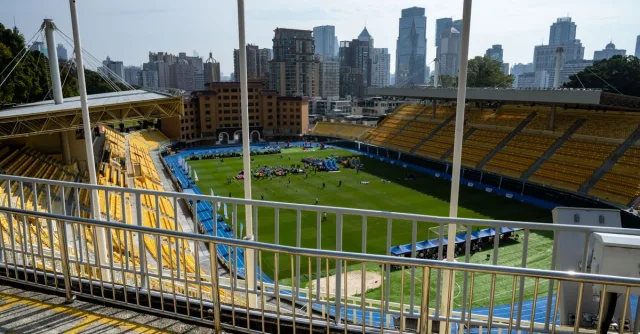 Wide-angle view of a Guangzhou sports stadium with city skyscrapers in the background.