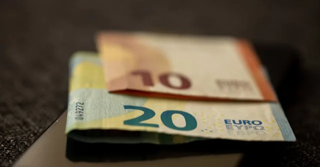 A detailed close-up shot of 10 and 20 euro banknotes placed on a smartphone, representing finance and technology.