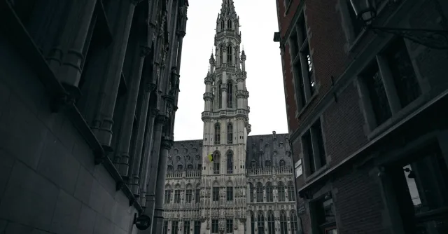 Dramatic view of the Brussels Town Hall in Gothic style, framed by narrow streets.