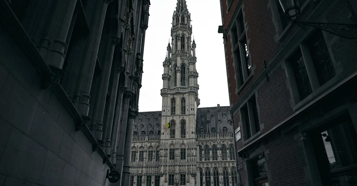 Dramatic view of the Brussels Town Hall in Gothic style, framed by narrow streets.