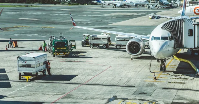 Ground crew preparing a commercial airplane for departure at an airport tarmac.