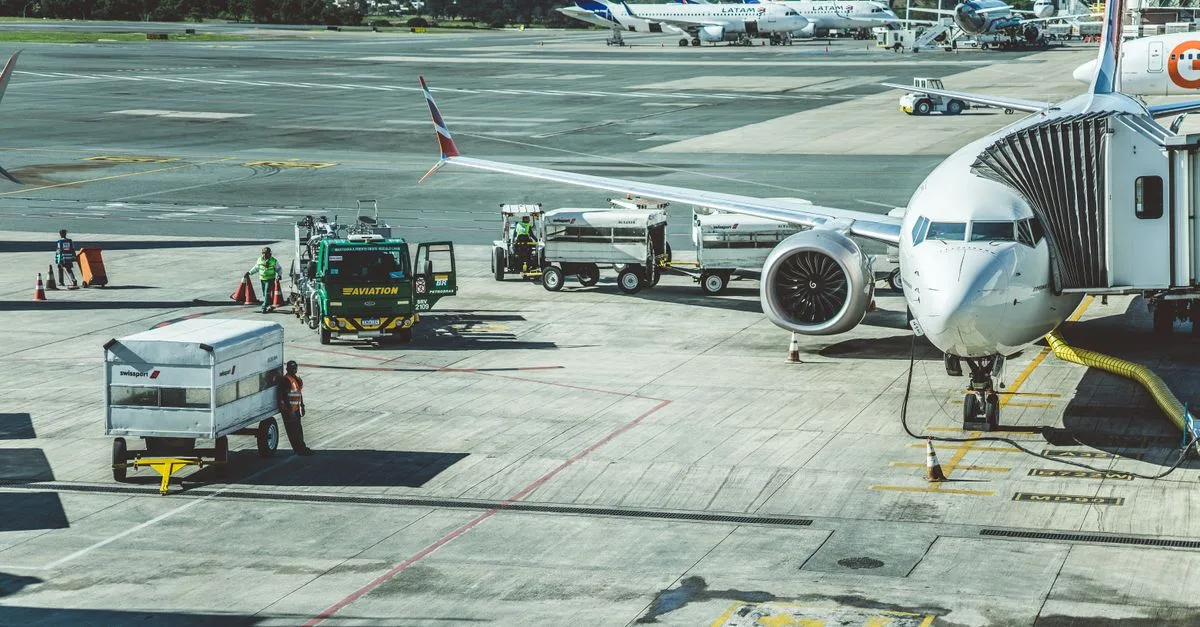 Ground crew preparing a commercial airplane for departure at an airport tarmac.