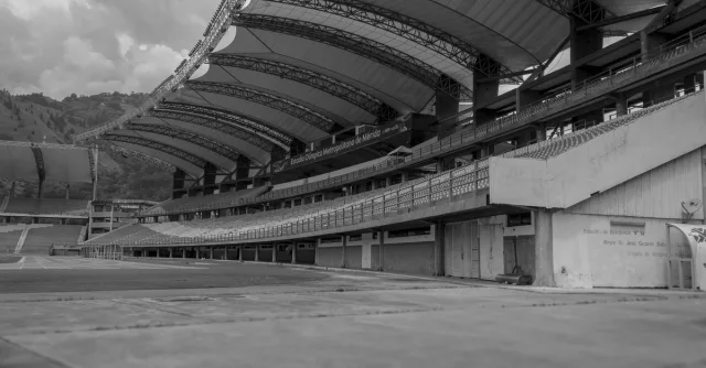 Monochrome view of an empty football stadium featuring modern architecture and expansive seating.