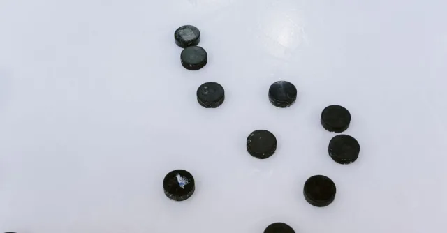 Multiple ice hockey pucks scattered on a smooth, frozen surface.