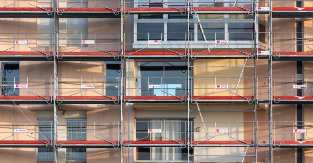 Scaffolding covers an urban building facade, capturing a construction site in detail.
