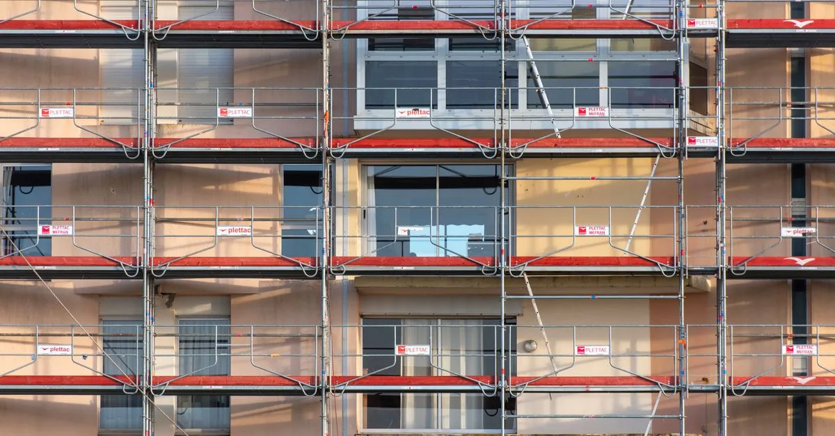 Scaffolding covers an urban building facade, capturing a construction site in detail.