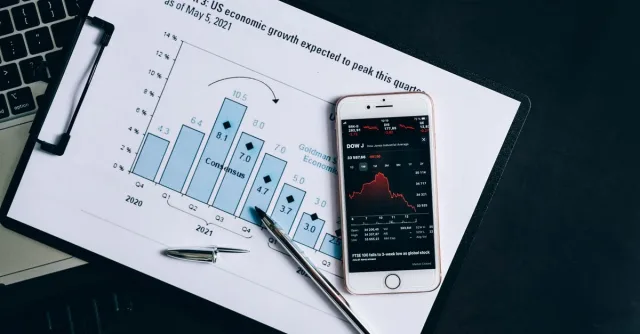A smartphone displaying stock data rests on a financial report graph.