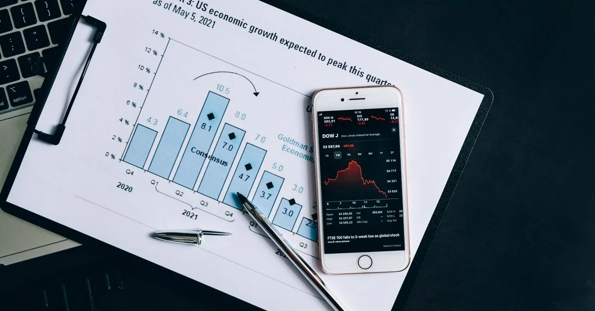 A smartphone displaying stock data rests on a financial report graph.
