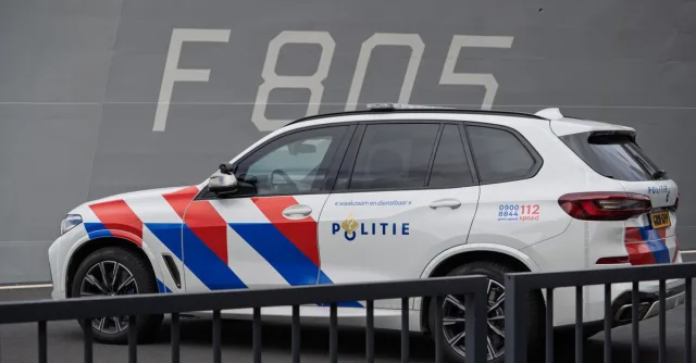 Dutch police SUV parked next to a naval ship marked F 805, highlighting law enforcement and military presence.