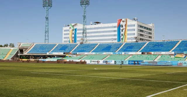 Empty stadium in Almaty, Kazakhstan on a sunny day, showcasing seating and infrastructure.