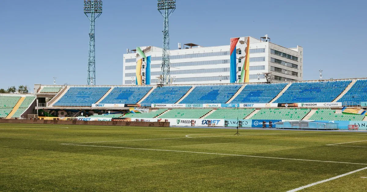 Empty stadium in Almaty, Kazakhstan on a sunny day, showcasing seating and infrastructure.