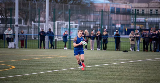 Rugby player running with ball during a match in Manchester, England.