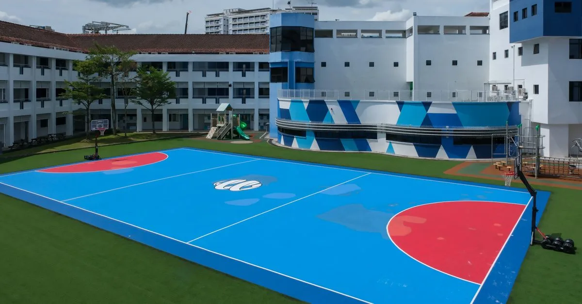Aerial view of a vibrant, modern schoolyard with a blue and red basketball court.