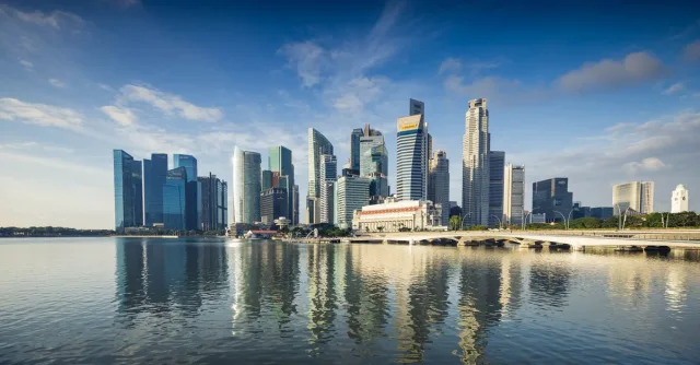 Capture of Singapore's modern skyline featuring reflective skyscrapers against a blue sky.