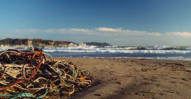 Colorful ropes piled on Kamakura beach, Japan, with ocean waves in the background.