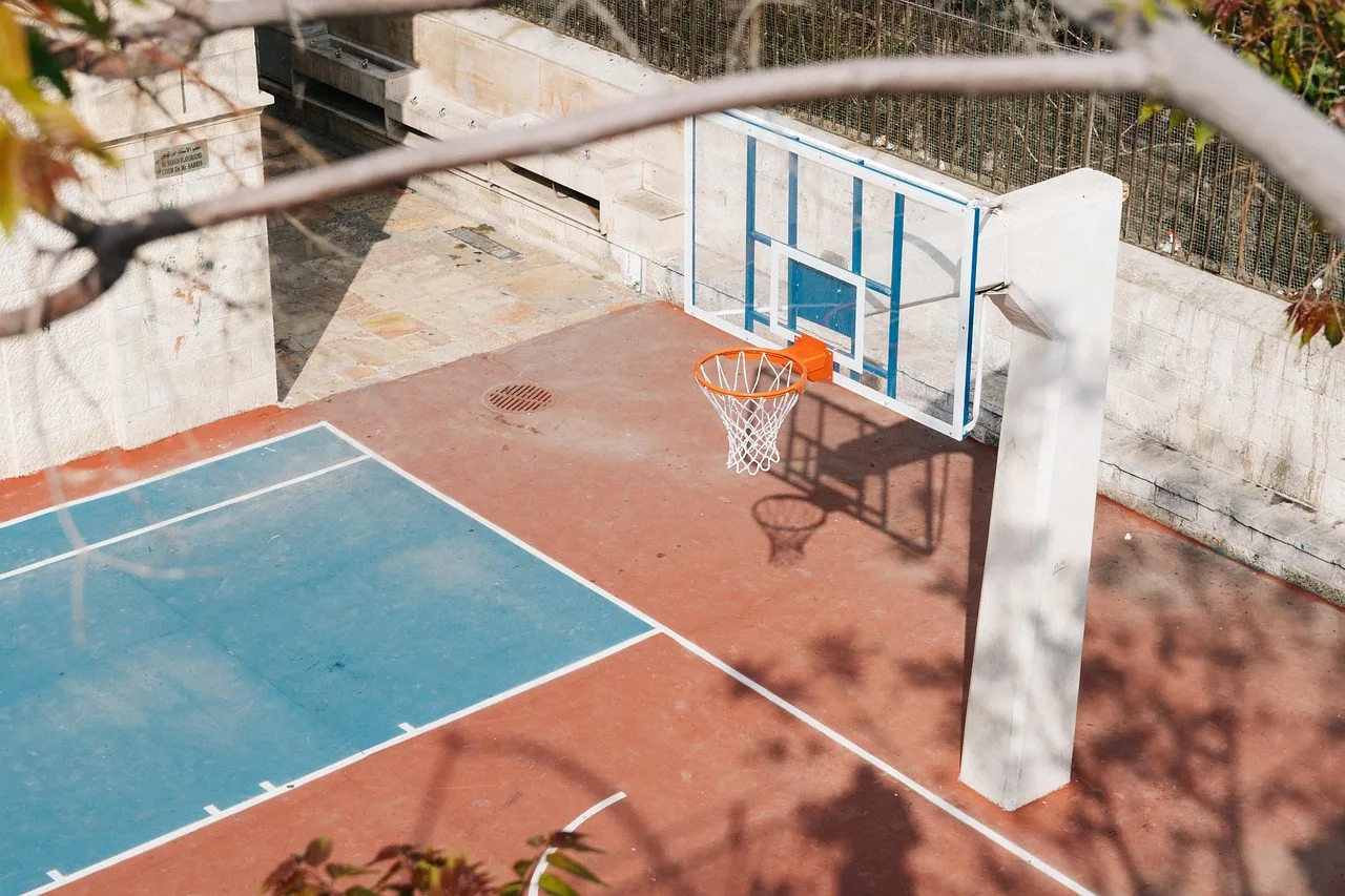 An empty professional basketball court under bright arena lighting.
