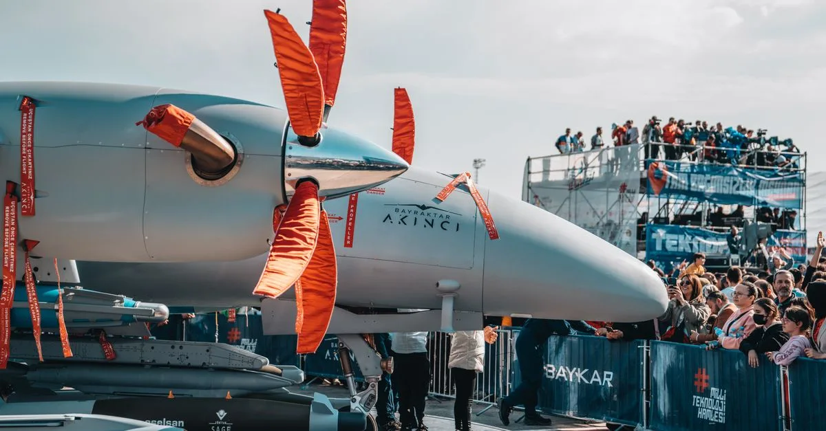 Military drone on display with large crowds at an airshow, showcasing aviation technology.