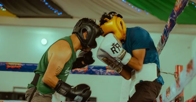 Two boxers engaged in a thrilling match wearing protective headgear and gloves.