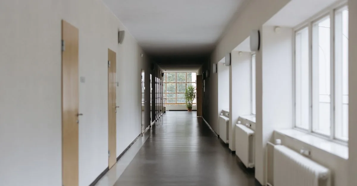 Spacious modern hallway with large windows and natural light reflecting off the floor.