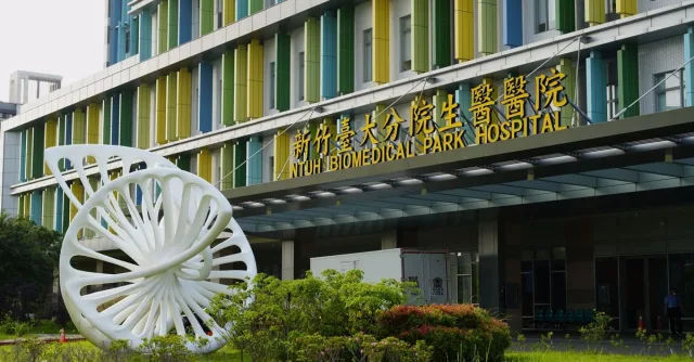Entrance to NTUH Biomedical Park Hospital with modern sculpture and colorful facade in Taiwan.