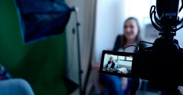 Woman being recorded in a professional studio setup, using video camera and lighting equipment.