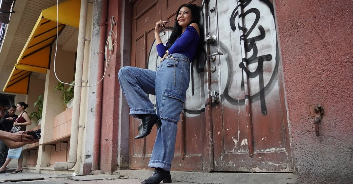 Stylish young woman posing for a street fashion photo shoot in front of graffiti-covered door.