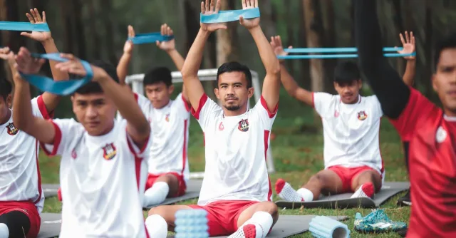 A group of young soccer players exercises with resistance bands during outdoor training.