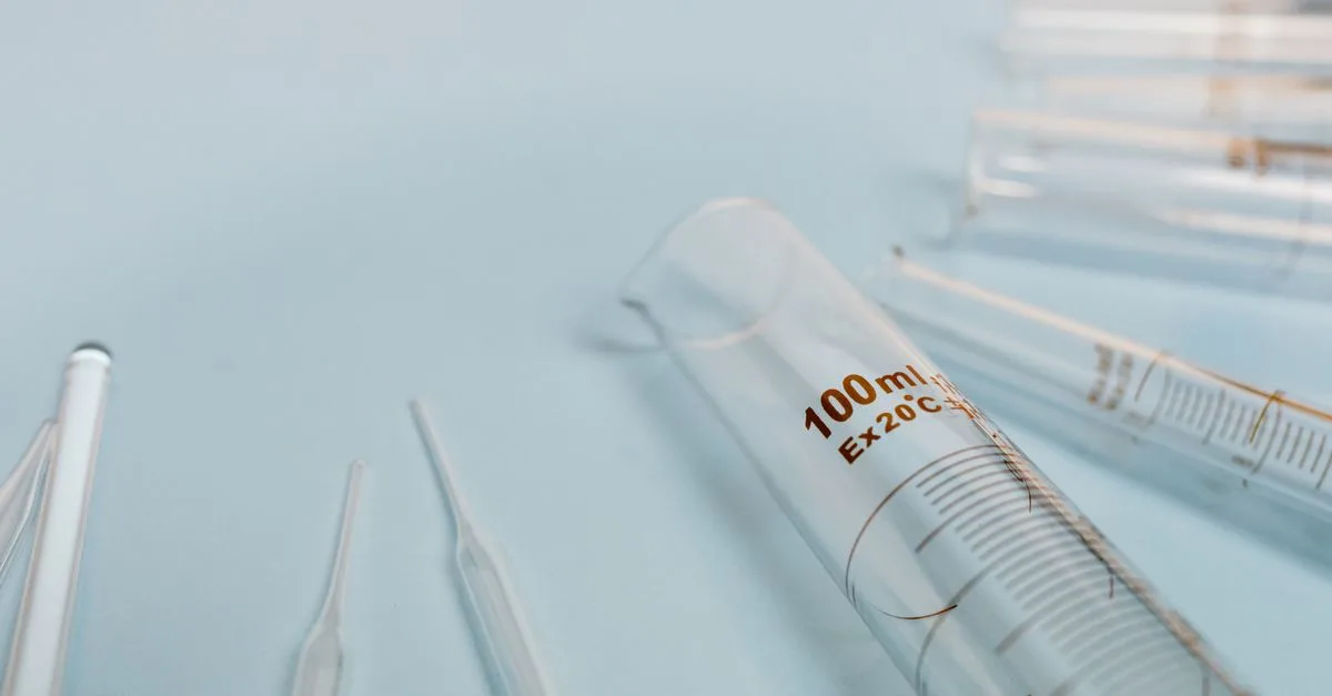 A collection of transparent glass test tubes on a soft blue surface, ideal for scientific research visuals.