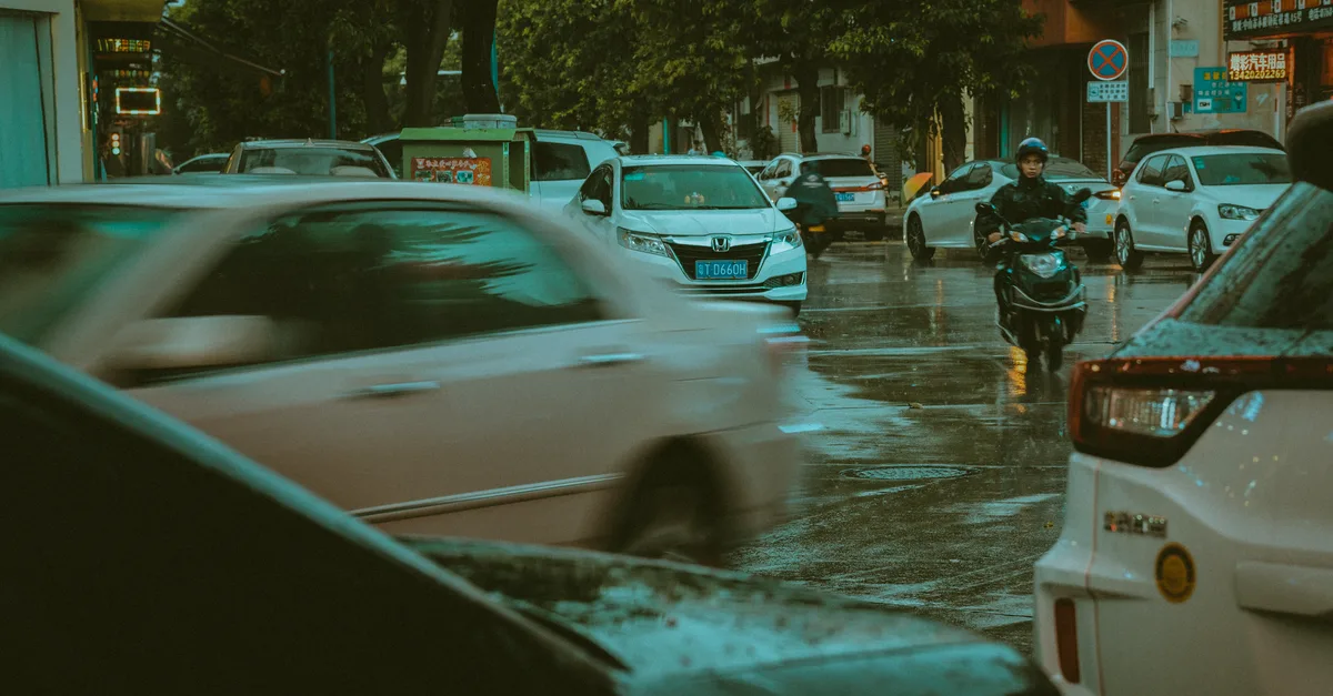 Dynamic scene of rainy day traffic in a Chinese city, highlighting motion and energy.