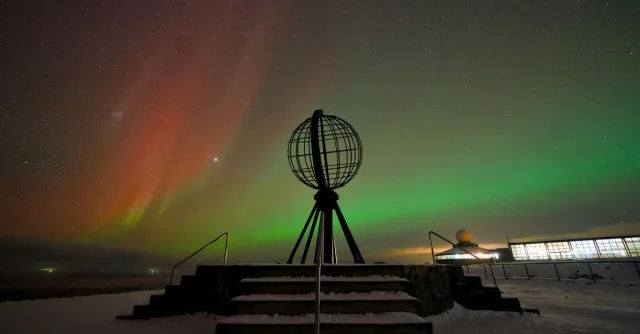 A breathtaking view of the Northern Lights over the North Cape, Norway's iconic globe monument.