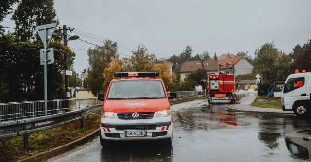 Fire trucks and emergency vehicles on a rainy street showcasing a firefighting operation in progress.
