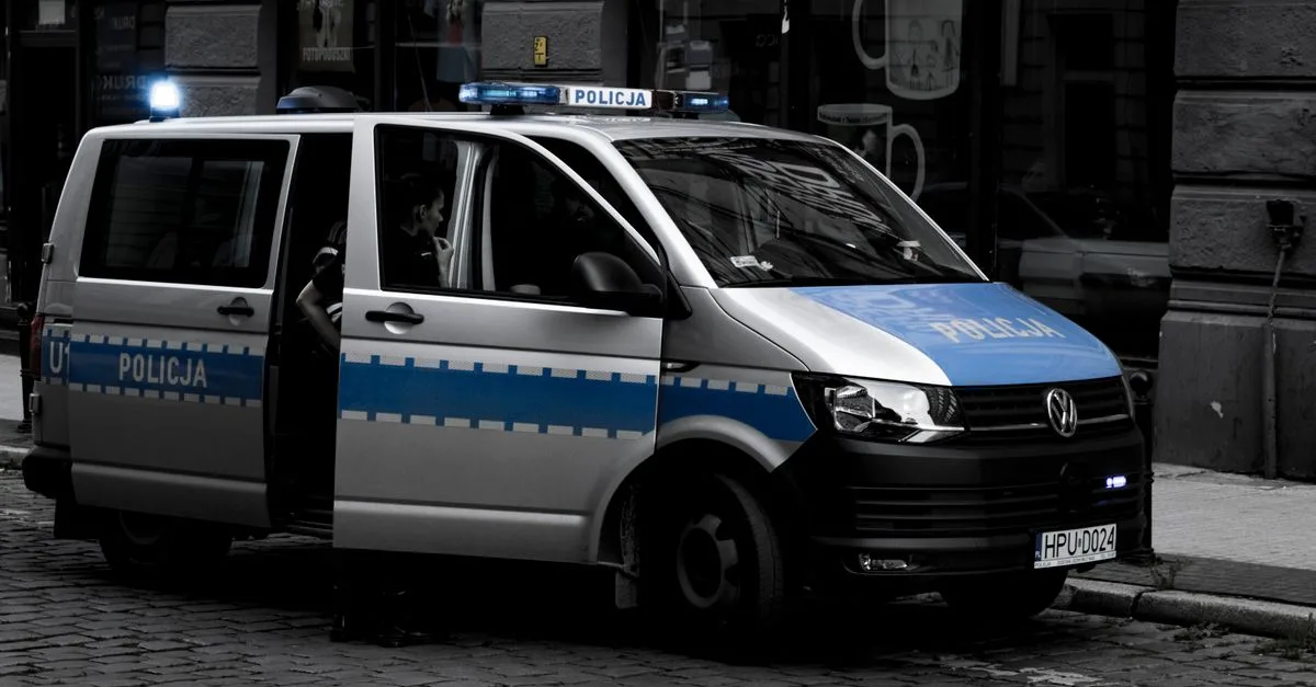 A police van parked on a cobblestone street in an urban setting.