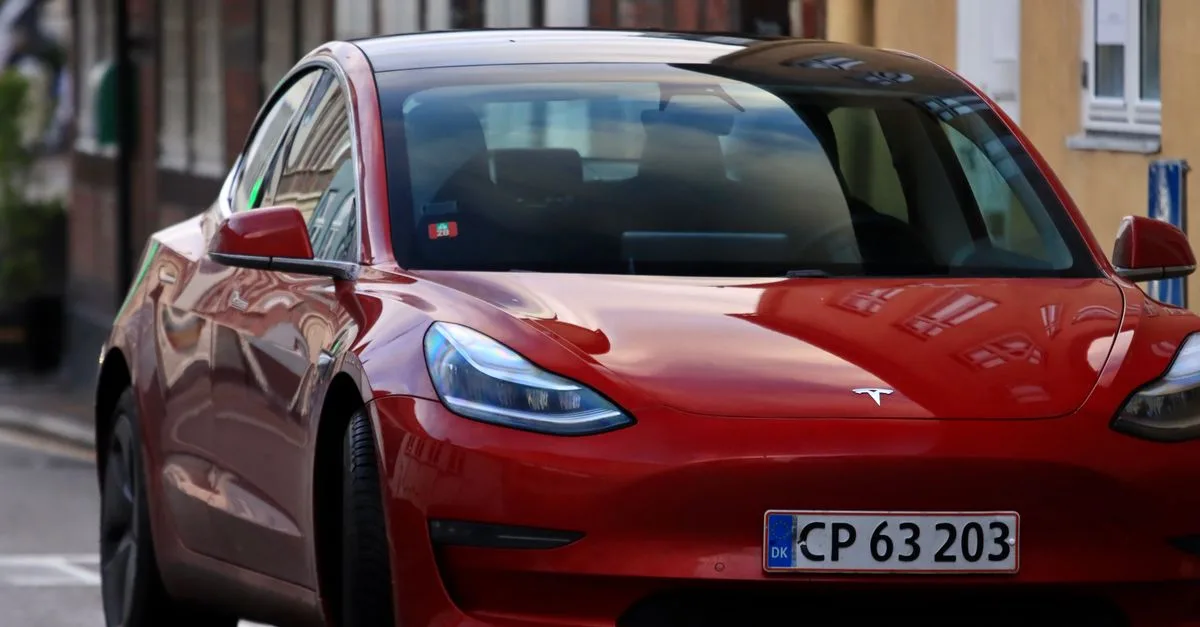 Striking red electric car with headlights on, parked on an urban street.