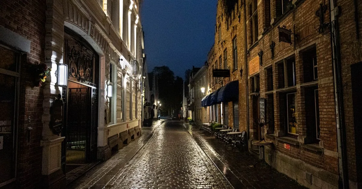 Cobblestone street in Bruges, Belgium, showcasing classic European architecture illuminated at night.