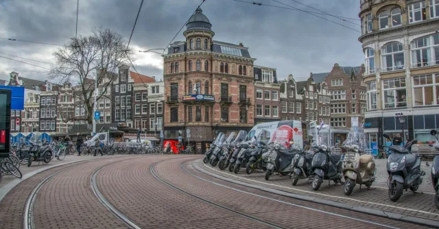 Dynamic street scene capturing Amsterdam's iconic architecture and scooters.