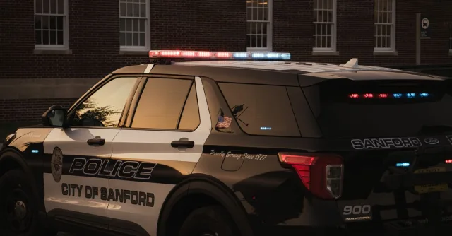Sanford police vehicle parked outdoors at twilight, showcasing red and blue lights.