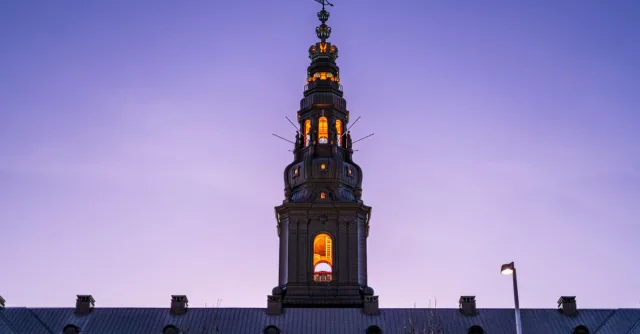 Stunning view of Christiansborg Palace illuminated against a twilight sky in Copenhagen, Denmark.