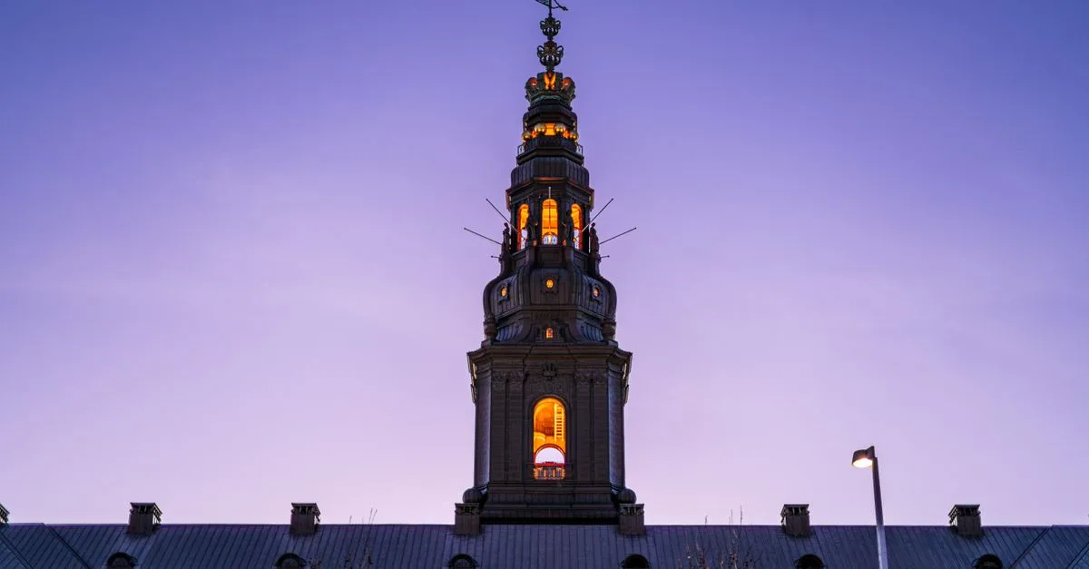 Stunning view of Christiansborg Palace illuminated against a twilight sky in Copenhagen, Denmark.