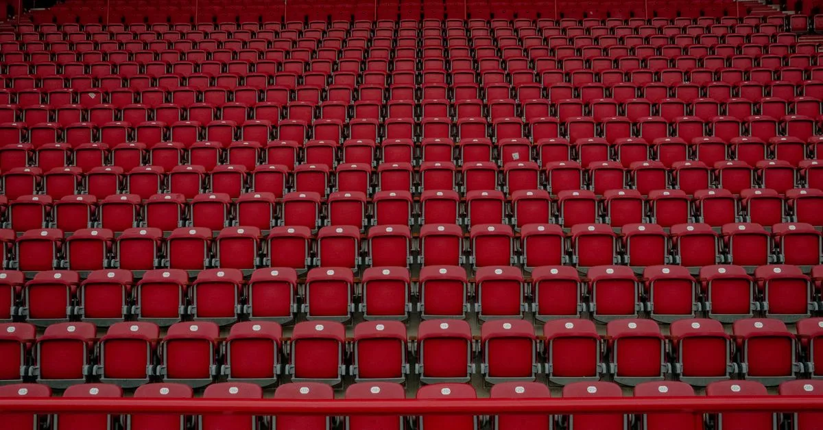 Rows of empty red seats in a Berlin stadium, creating a symmetrical pattern.
