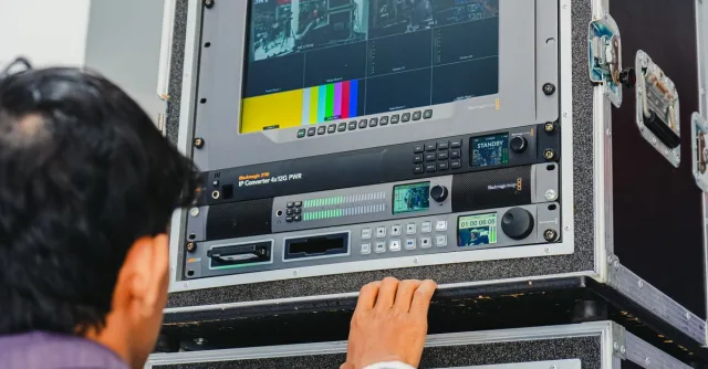 A technician manages professional broadcasting equipment in a control room setting.